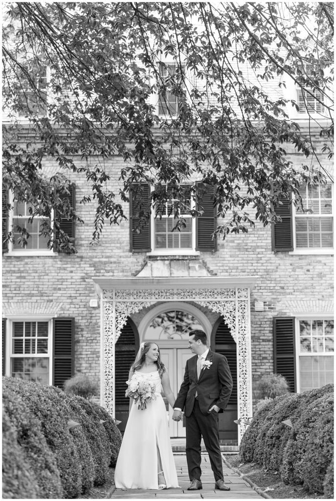 black and white photo of couple holding hands in front of home at this Drumore Estate Summer Wedding