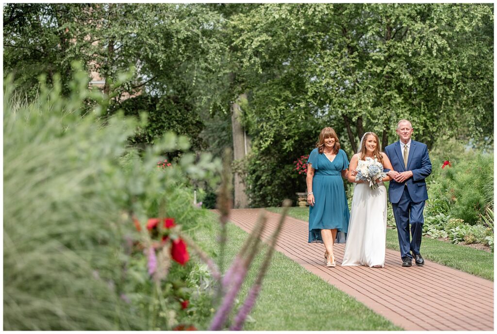 bride being walked down the brick aisle by her parents for this Drumore Estate Summer Wedding