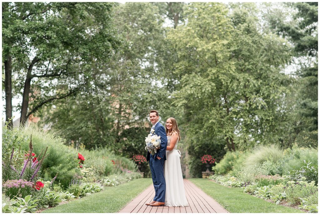 bride hugging her groom from behind on brick pathway at this Drumore Estate Summer Wedding in lancaster pennsylvania