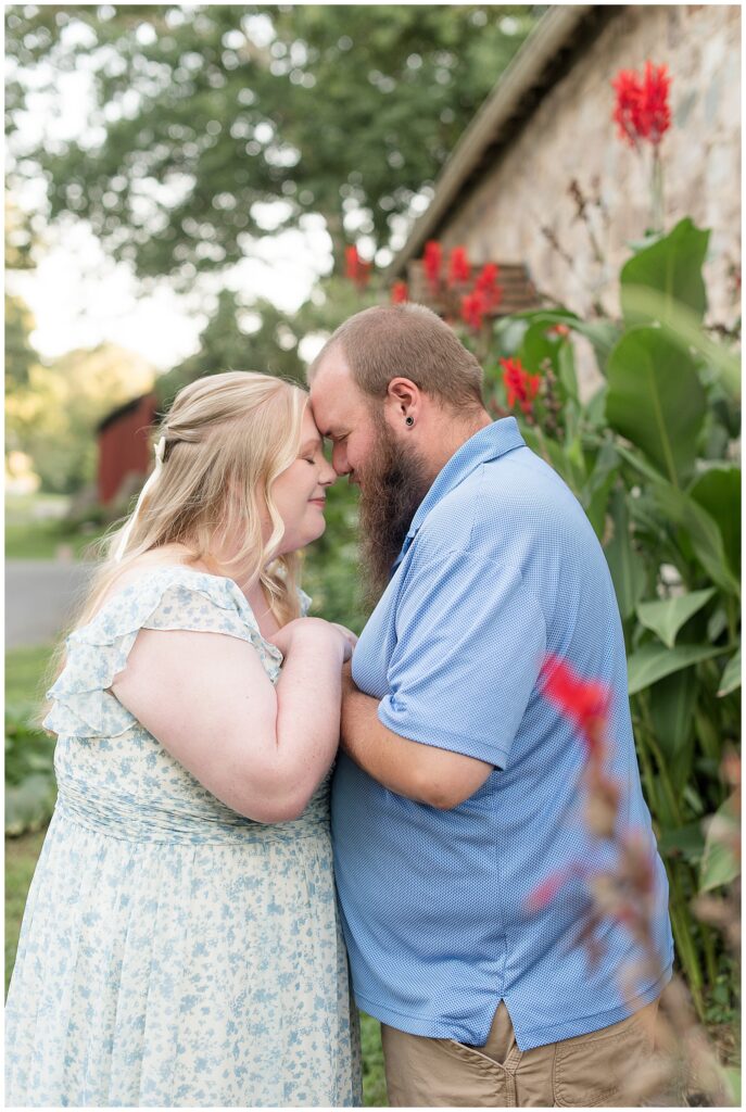 couple resting their foreheads together by cana lilies at this Historic Poole Forge Summer Engagement Session