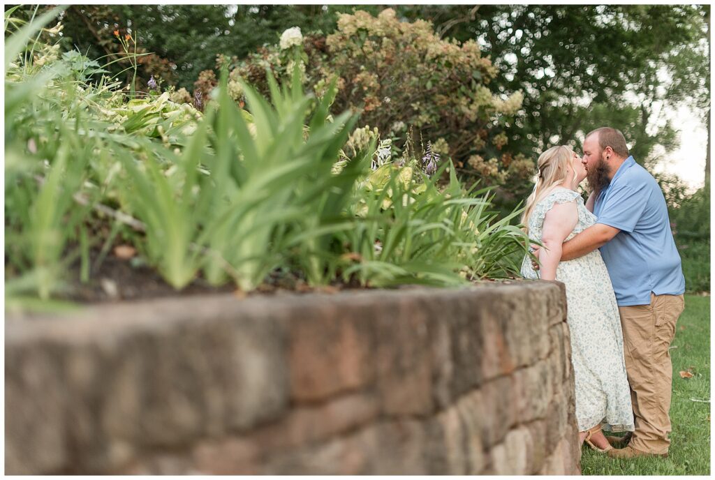 couple kissing by stone wall at sunset for this Historic Poole Forge Summer Engagement Session