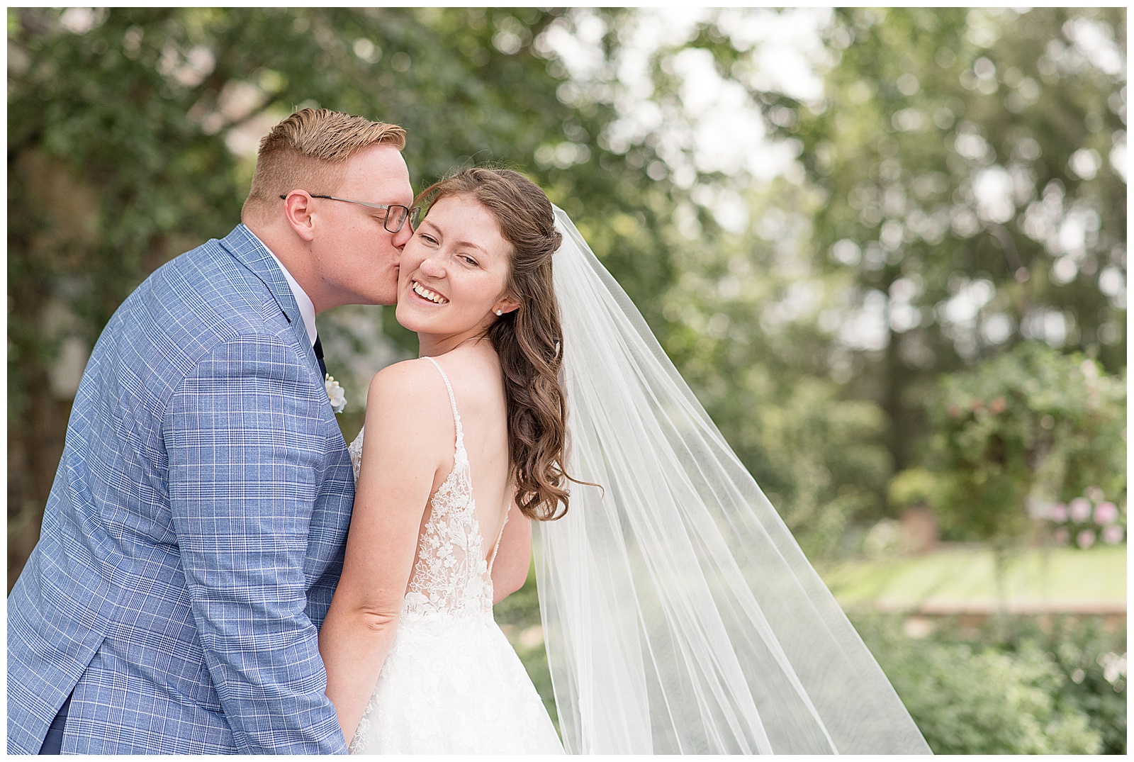 groom kissing his bride's right cheek as she smiles at the camera for this york county wedding