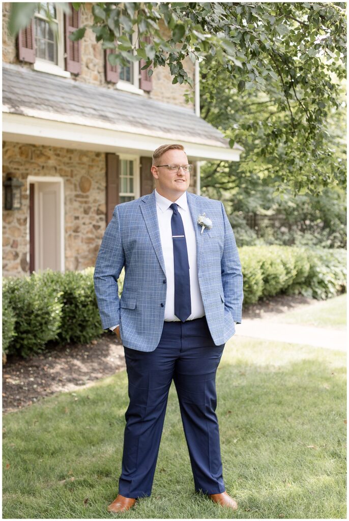 groom in blue suit with hands in pockets looking off into distance for this Lakeview Farms Summer Wedding