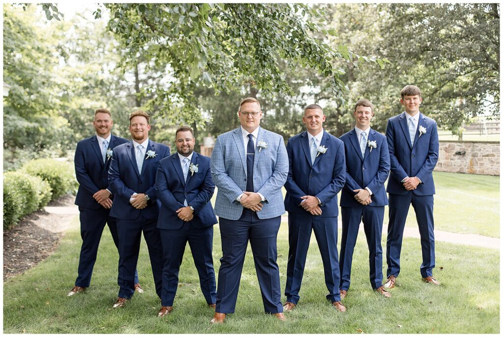 groom with his six groomsmen standing in a "v" wearing navy blue suits for this Lakeview Farms Summer Wedding