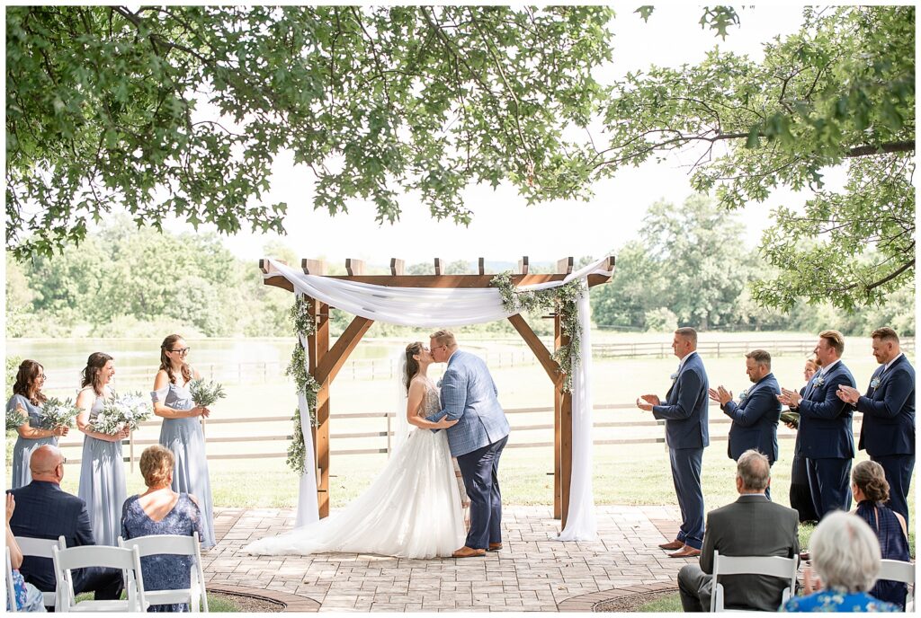 couple sharing their first kiss during outdoor wedding ceremony at this Lakeview Farms Summer Wedding