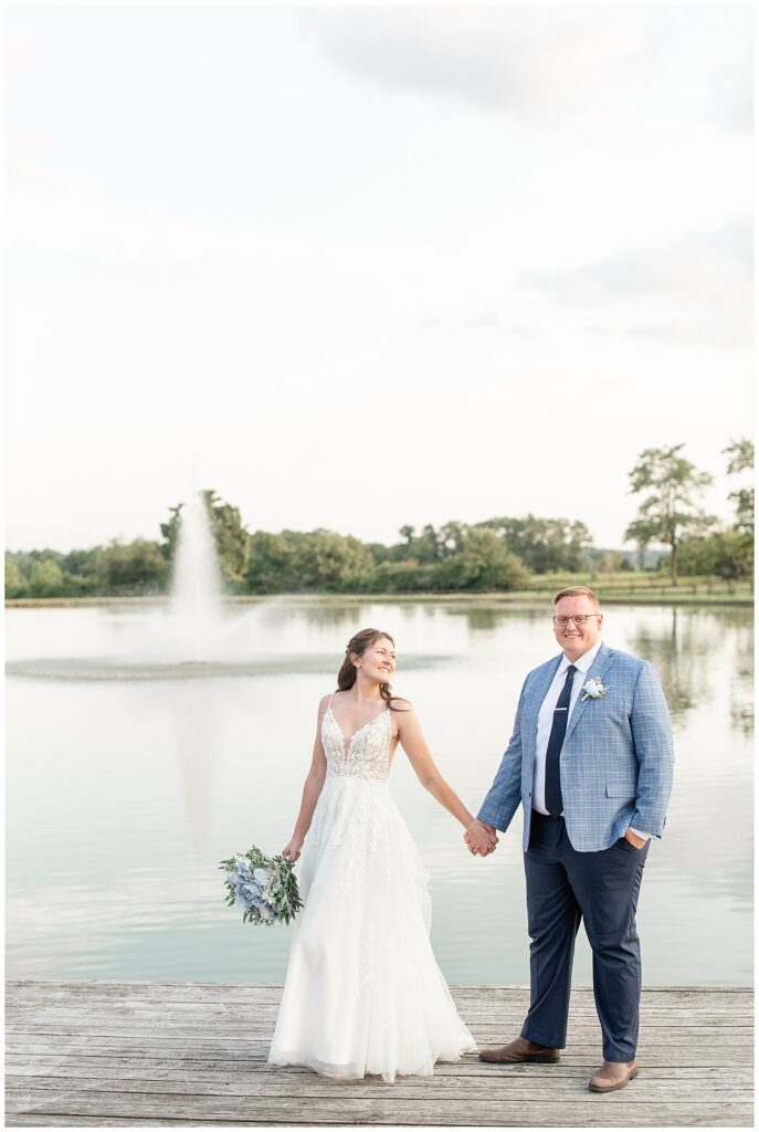 couple holding hands by beautiful lake on summer evening at this Lakeview Farms Summer Wedding in dover pennsylvania
