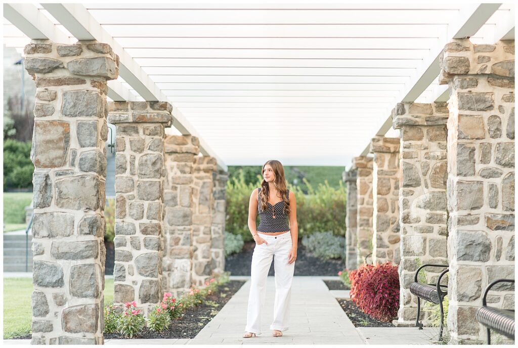 senior girl with right hand on hip standing between stone columns for this Summer Masonic Village Senior Session