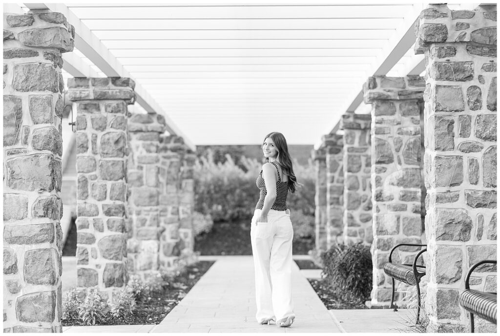 black and white photo of girl walking away from camera and looking back over left shoulder for this Summer Masonic Village Senior Session