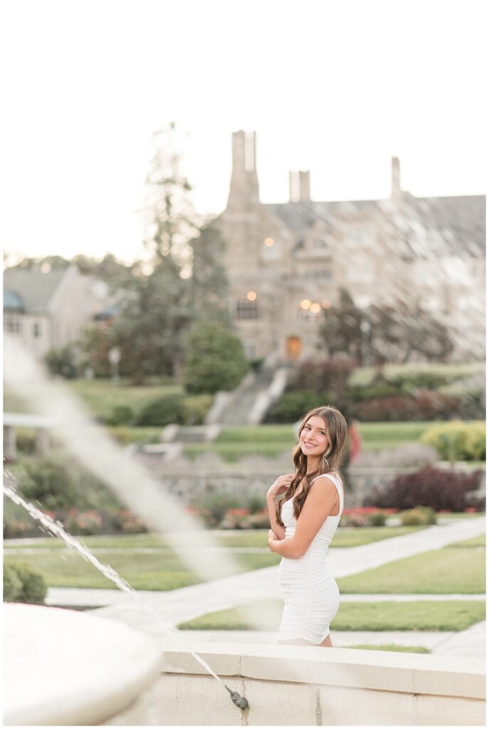 senior girl by fountain with large building in background for this Summer Masonic Village Senior Session