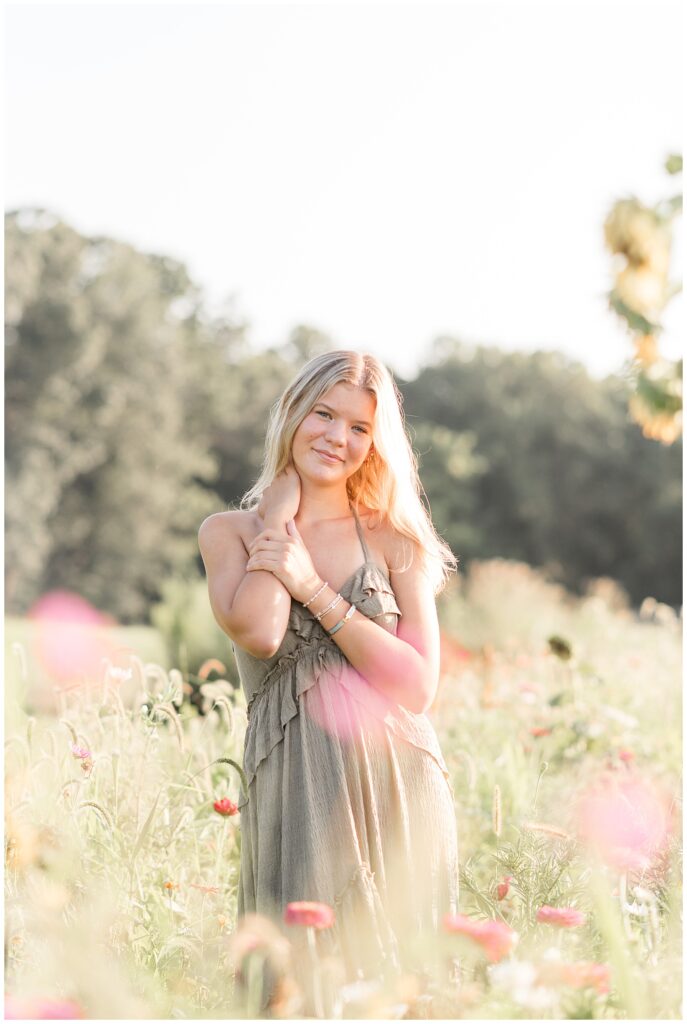 senior girl posing with right hand on right shoulder for this Summer Wildflower Field Senior Session