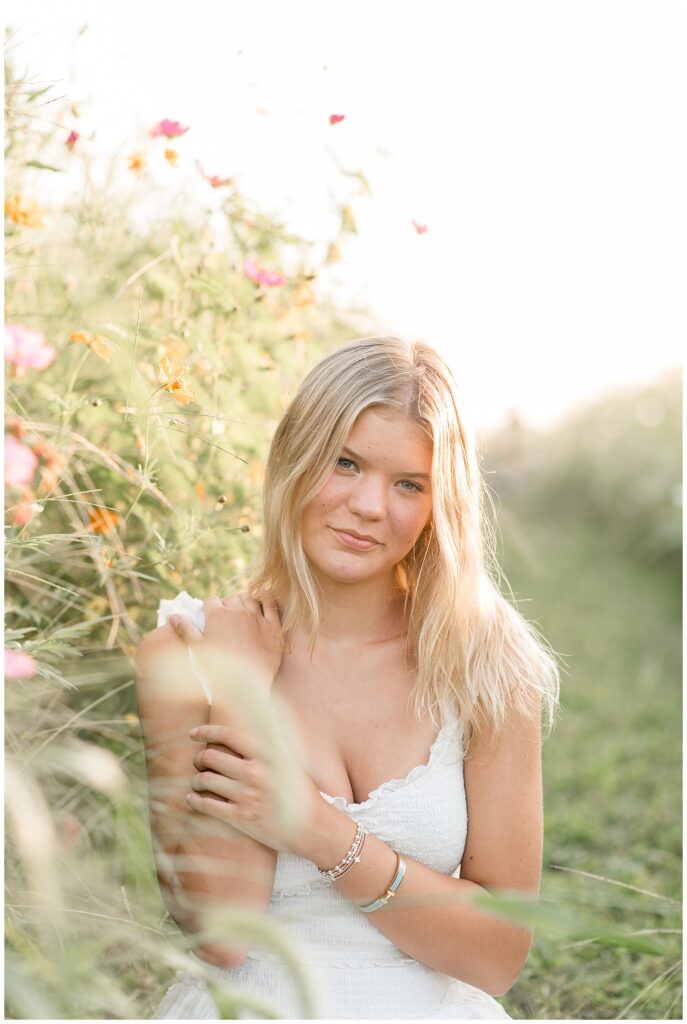 class of 2026 senior girl by patch of wildflowers in lancaster county for this Summer Wildflower Field Senior Session