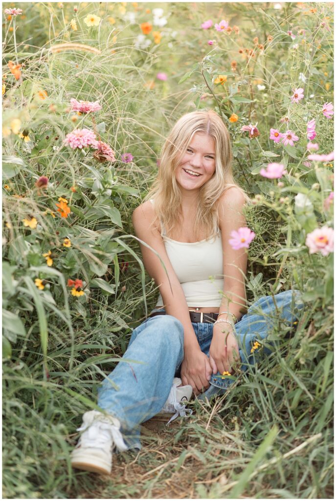senior girl sitting among the wildflowers for this Summer Wildflower Field Senior Session