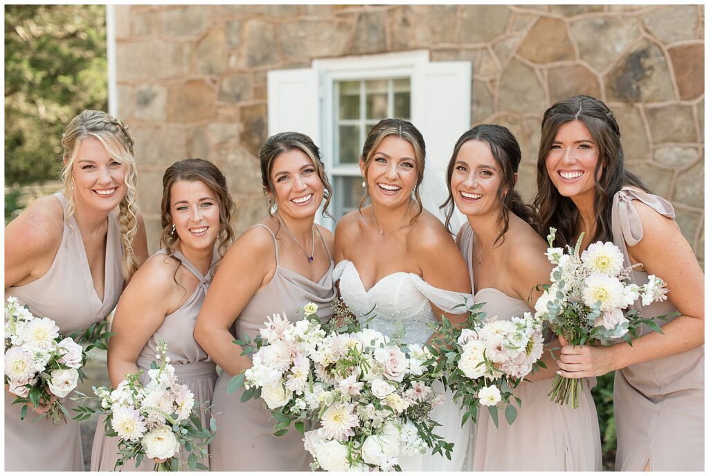 bride with her five bridesmaids in champagne colored gowns holding bouquets of white dahlias for this Elizabeth Furnace Fall Wedding