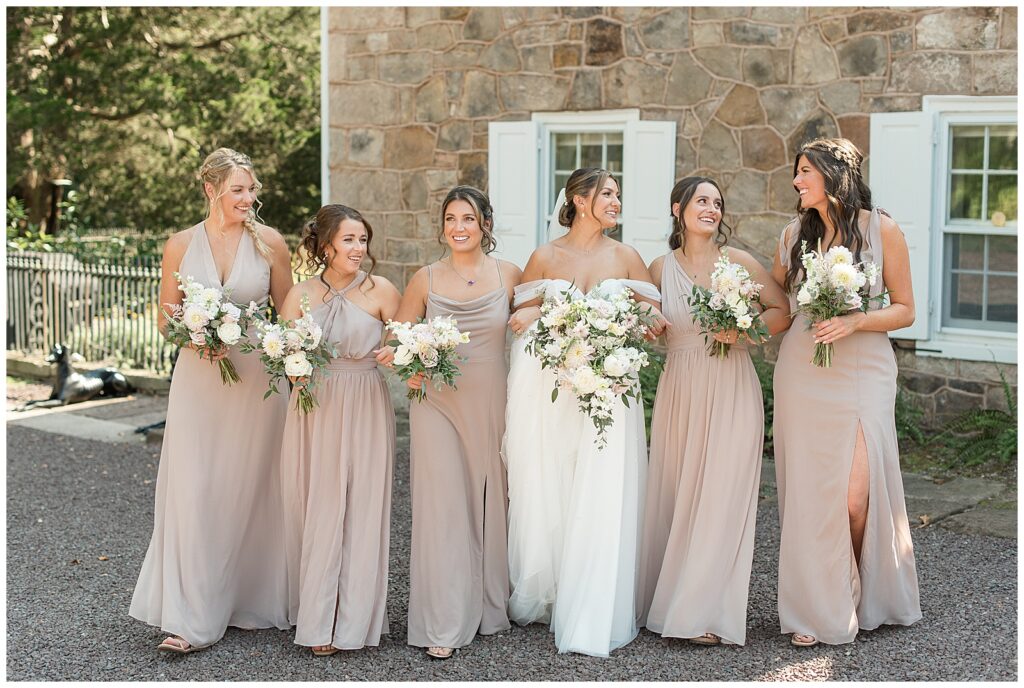 bride and bridesmaids walking towards camera by stone building for this Elizabeth Furnace Fall Wedding