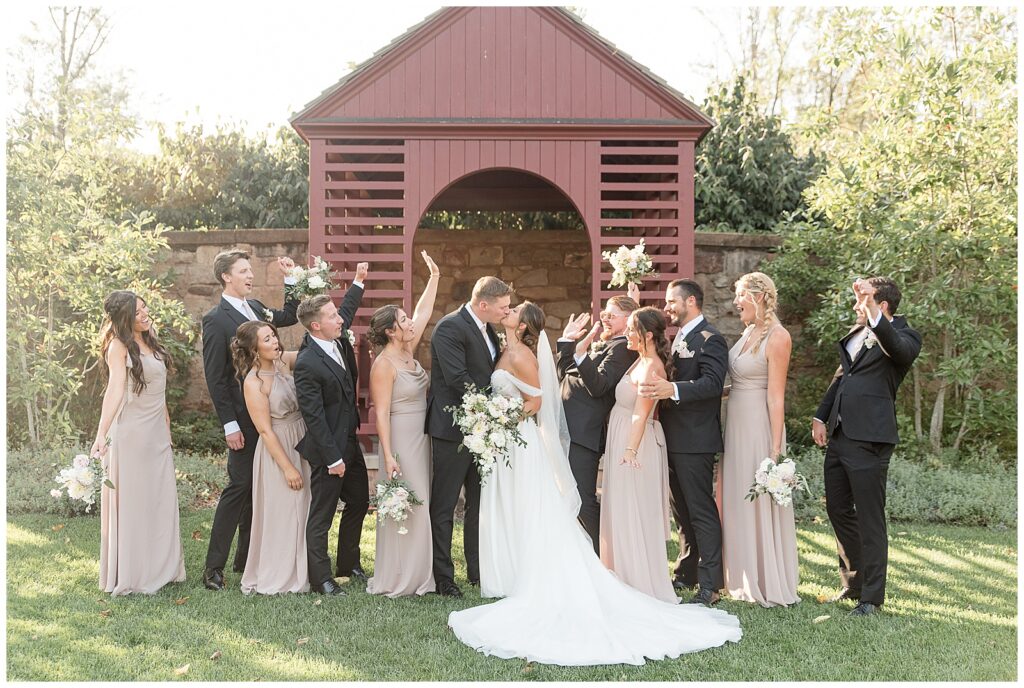 couple kissing as their bridal party cheers for this Elizabeth Furnace Fall Wedding in lititz pennsylvania