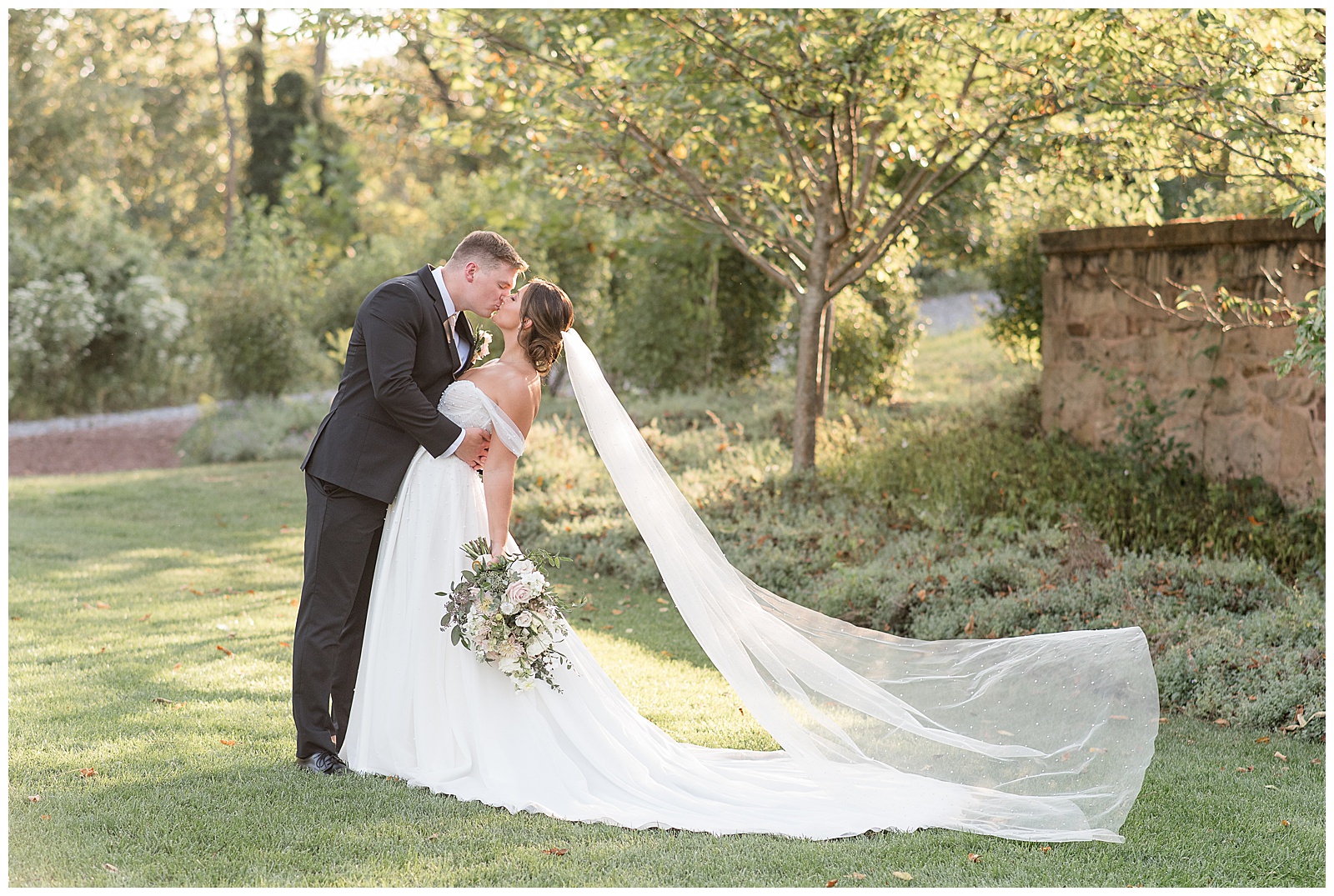 bride and groom kissing with bride's long veil extended behind her for this Elizabeth Furnace Fall Wedding