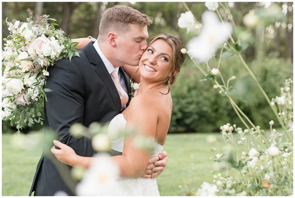 groom kissing bride's right cheek as she looks back over her left shoulder for this Elizabeth Furnace Fall Wedding