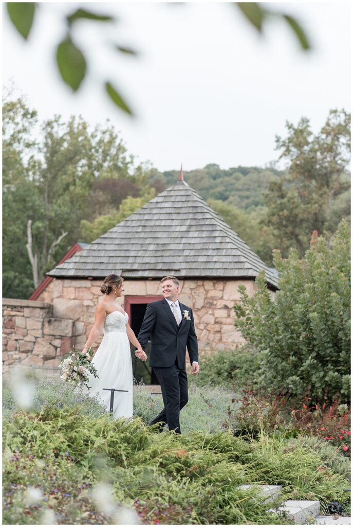 couple holding hands and walking around landscaped property for this Elizabeth Furnace Fall Wedding