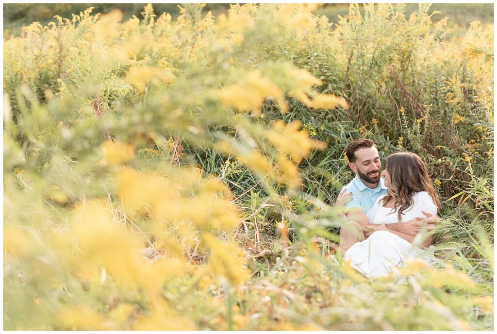 couple sitting together in field of yellow wildflowers for this Fall Hibernia Park Engagement Session