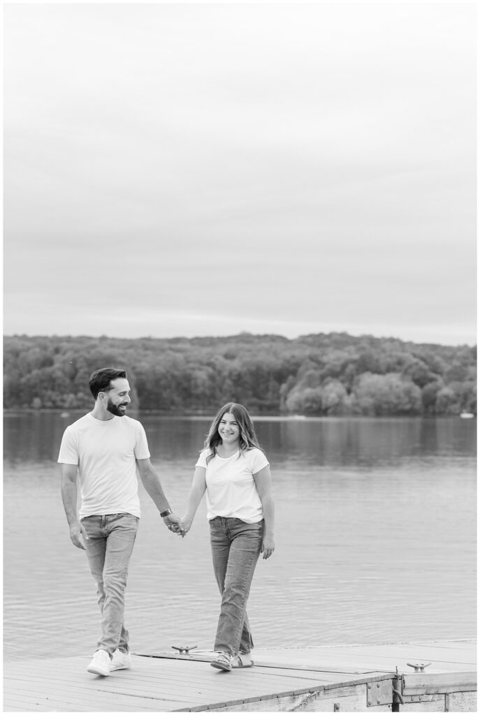 black and white photo of couple holding hands on dock by lake for this Fall Hibernia Park Engagement Session