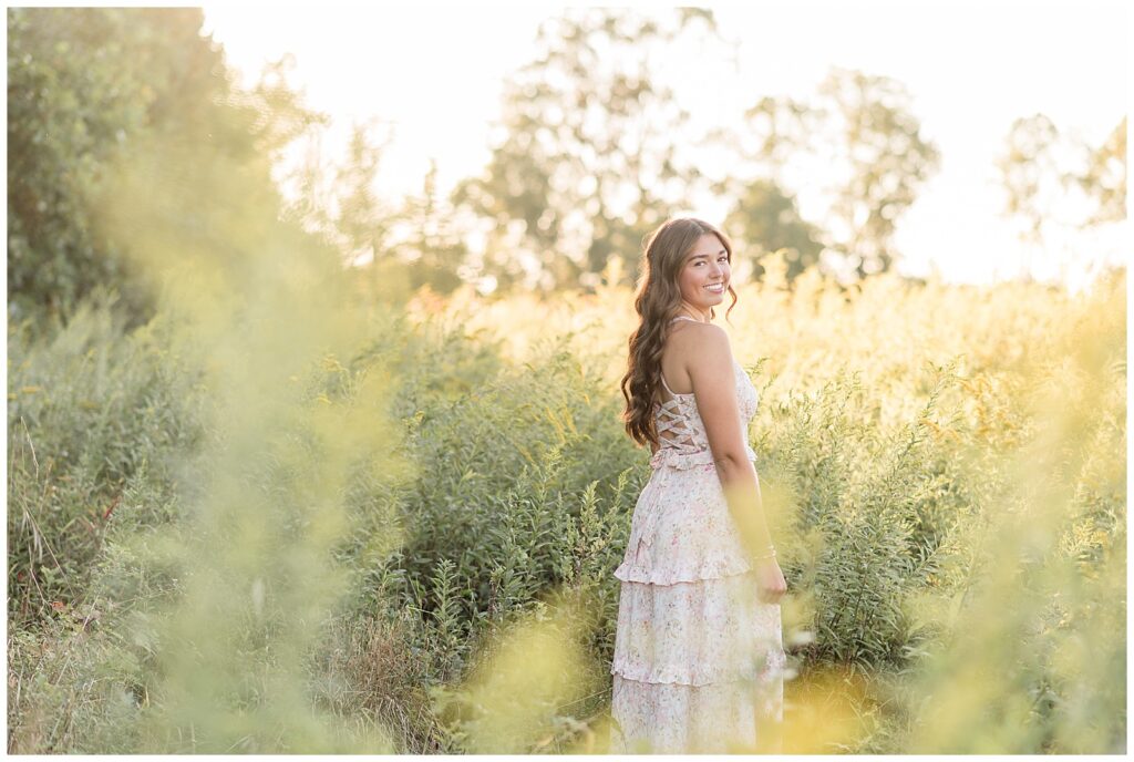senior girl in white lacy gown looking back over right shoulder at sunset for this Hibernia Park Senior Session