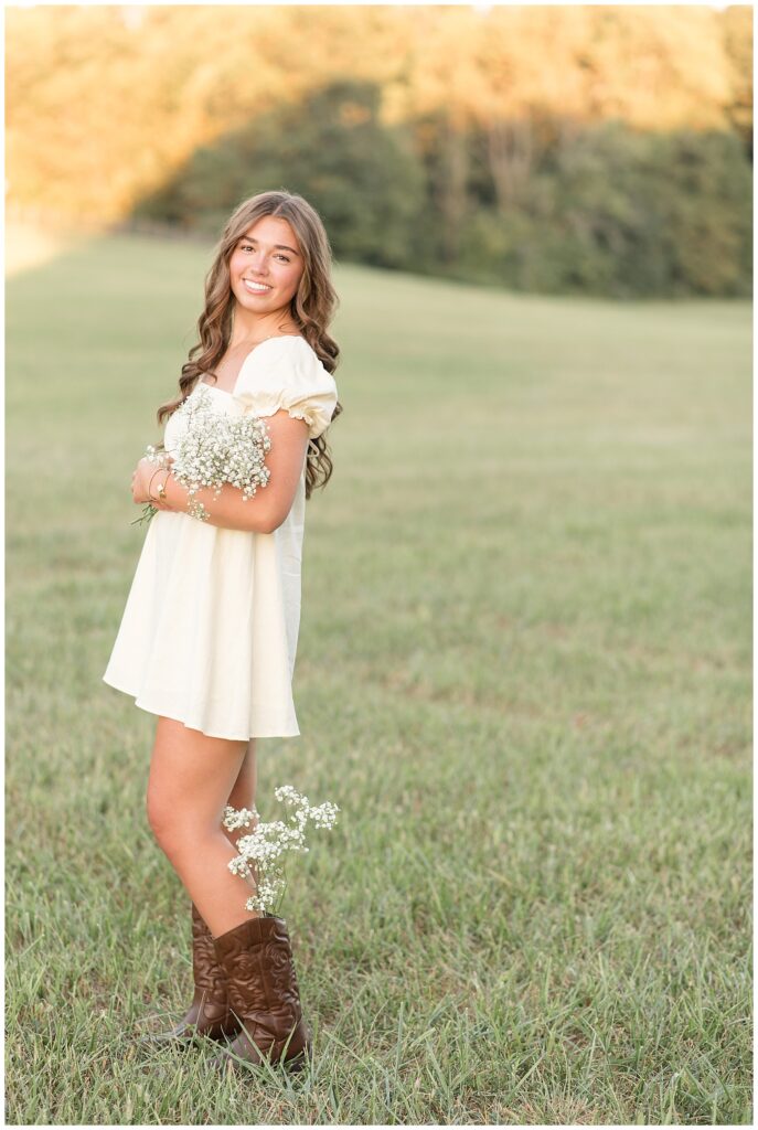 senior girl hugging bouquet of white wildflowers in grass field for this Hibernia Park Senior Session
