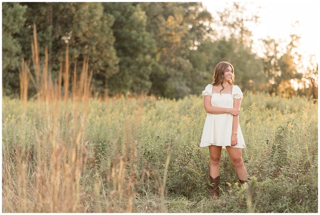 senior girl in field at sunset with tall grasses looking toward left shoulder for this Hibernia Park Senior Session