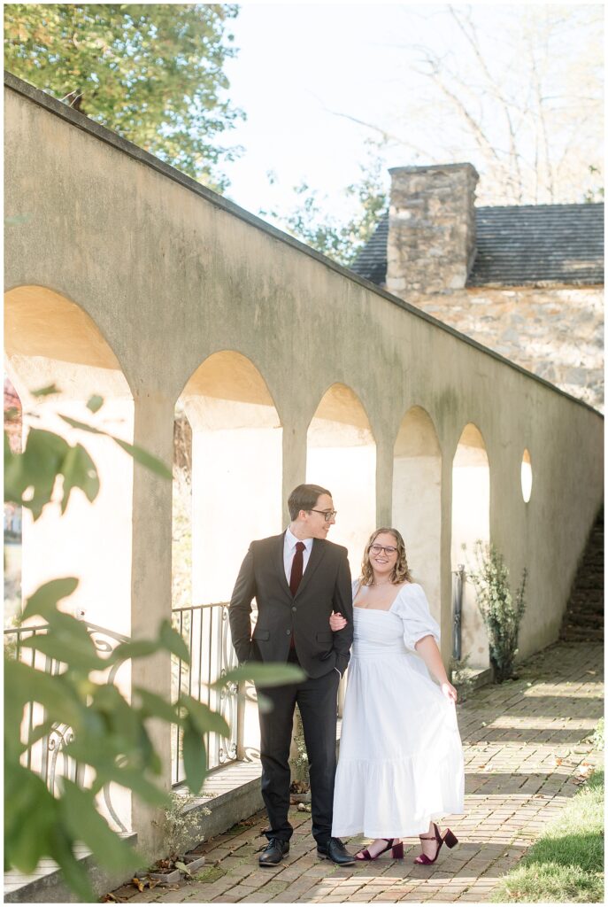 couple standing close by arched walkway for this Conestoga House and Gardens Engagement Session