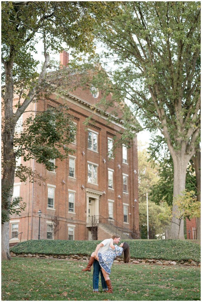 guy dipping girl back in grassy lawn by brick building for this Downtown Bethlehem Engagement Session