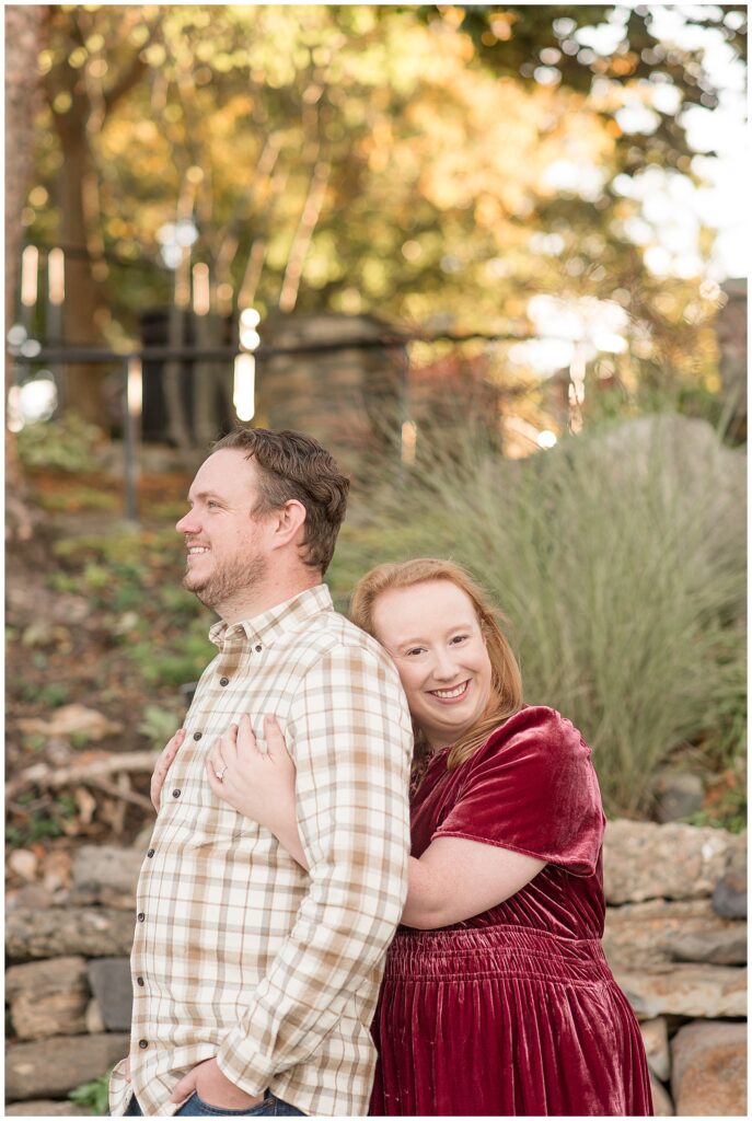 woman hugging man from behind as she smiles at camera for this Downtown New Hope Engagement Session