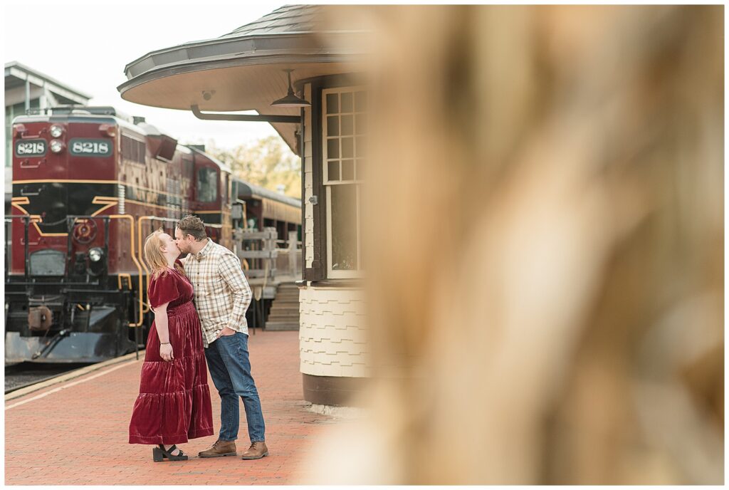 couple kissing by old train station for this Downtown New Hope Engagement Session