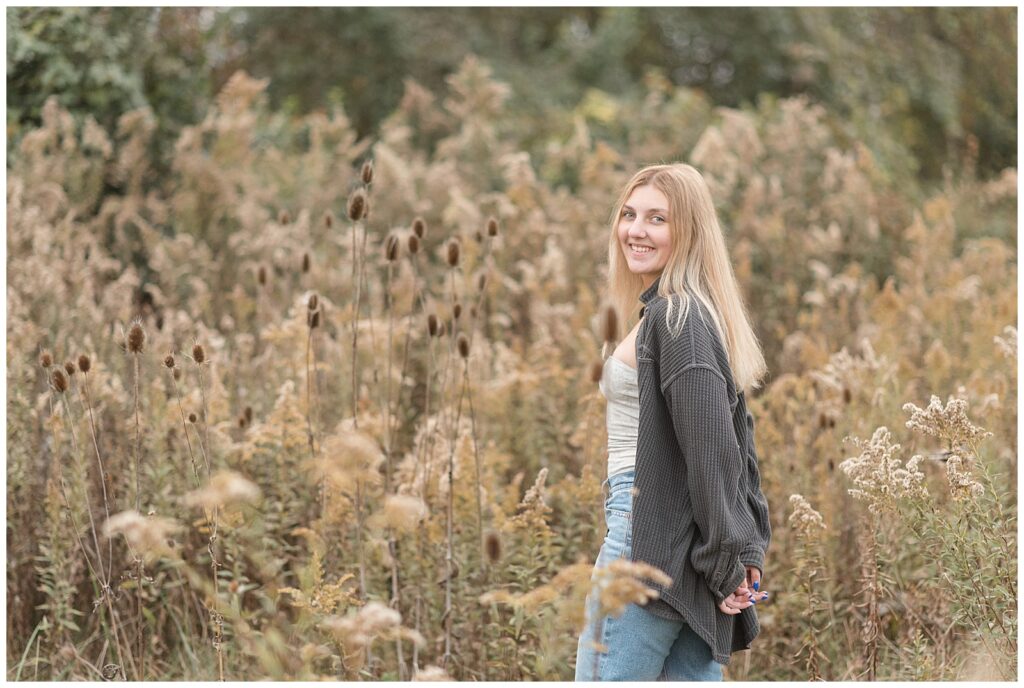 senior girl looking over left shoulder with hands in back pockets for this Fall Overlook Park Senior Session