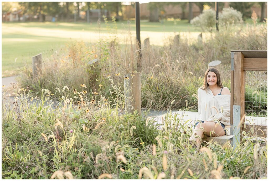 senior girl sitting by wildflowers for this Longs Park Fall Senior Session