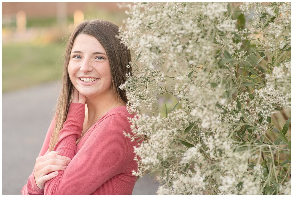 senior girl in pink shirt standing by white bush for this Longs Park Fall Senior Session