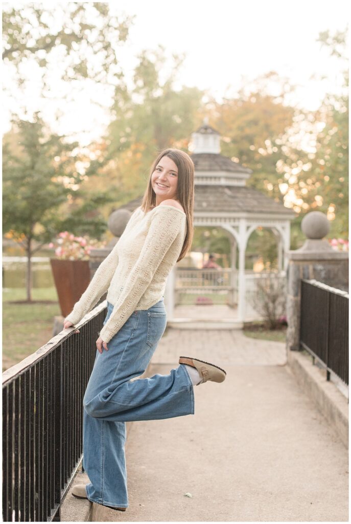 senior girl on bridge with left heel kicked up behind her for this Longs Park Fall Senior Session