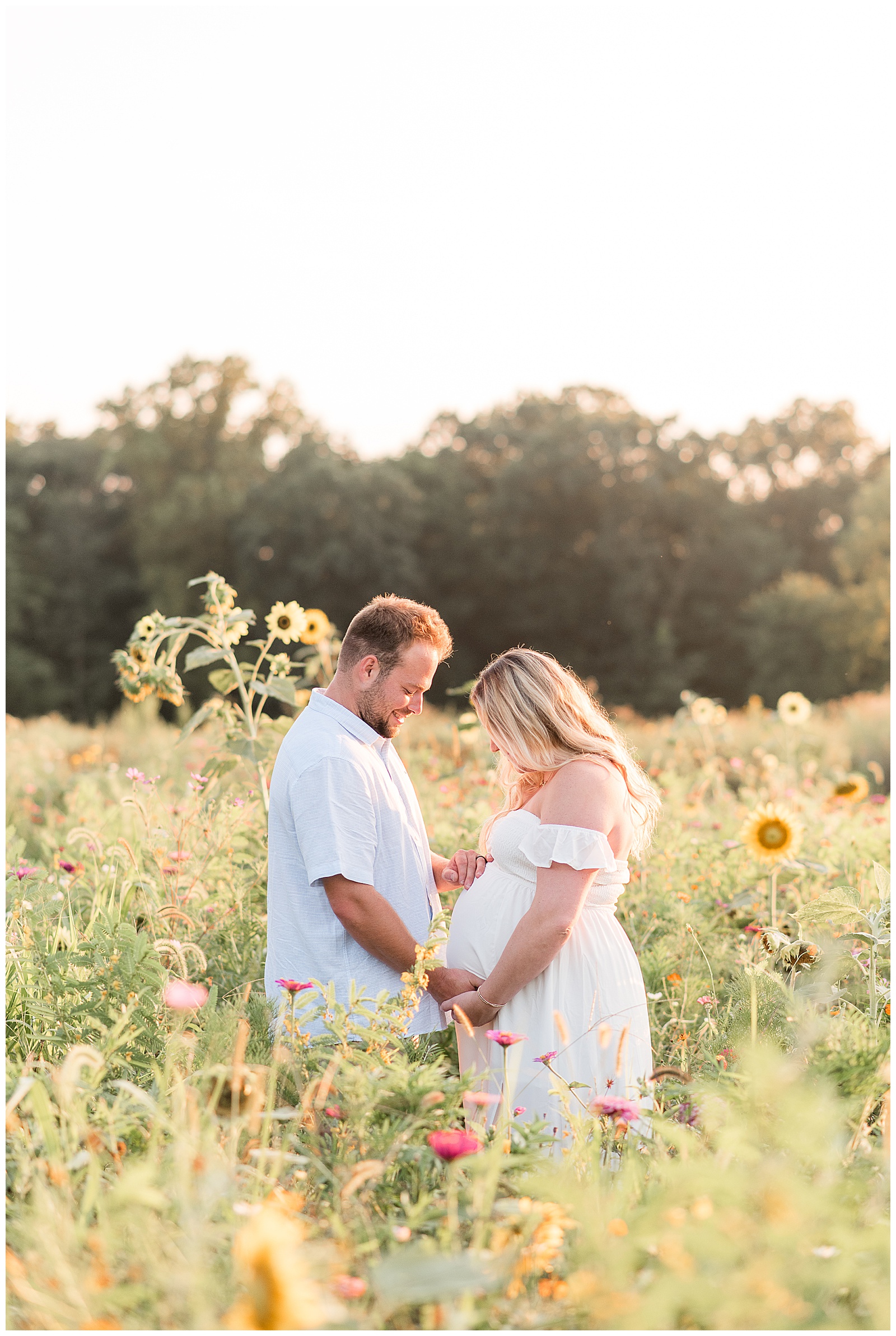 couple holding hands and looking down a wife's pregnant belly for this Wildflower Overlook Maternity and Lifestyle Newborn Session