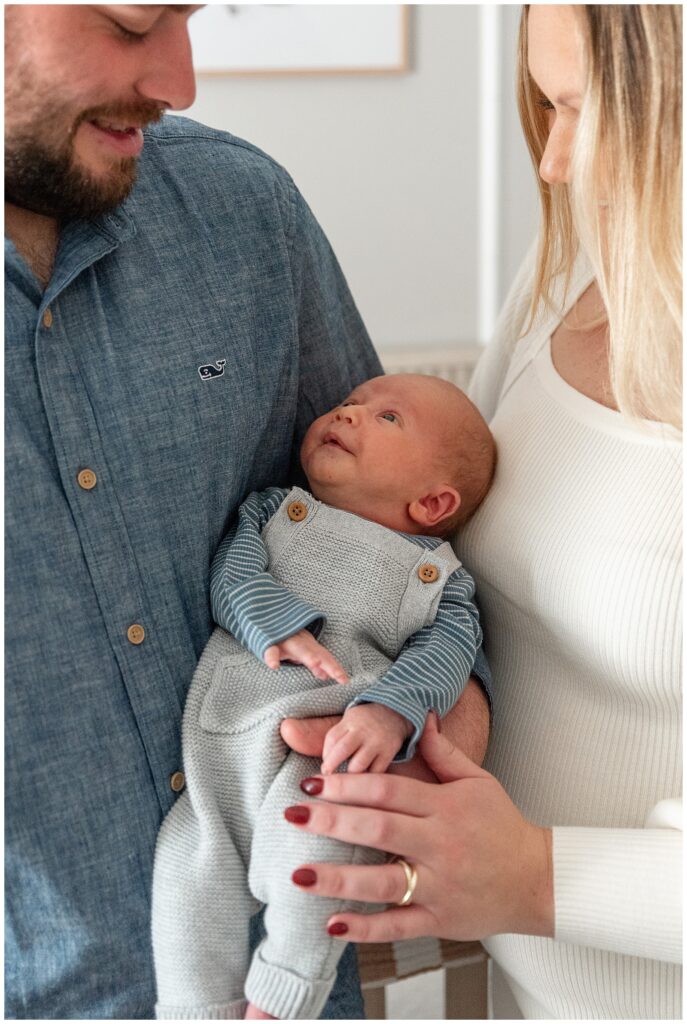couple looking down at newborn as baby looks up at his daddy for this Wildflower Overlook Maternity and Lifestyle Newborn Session