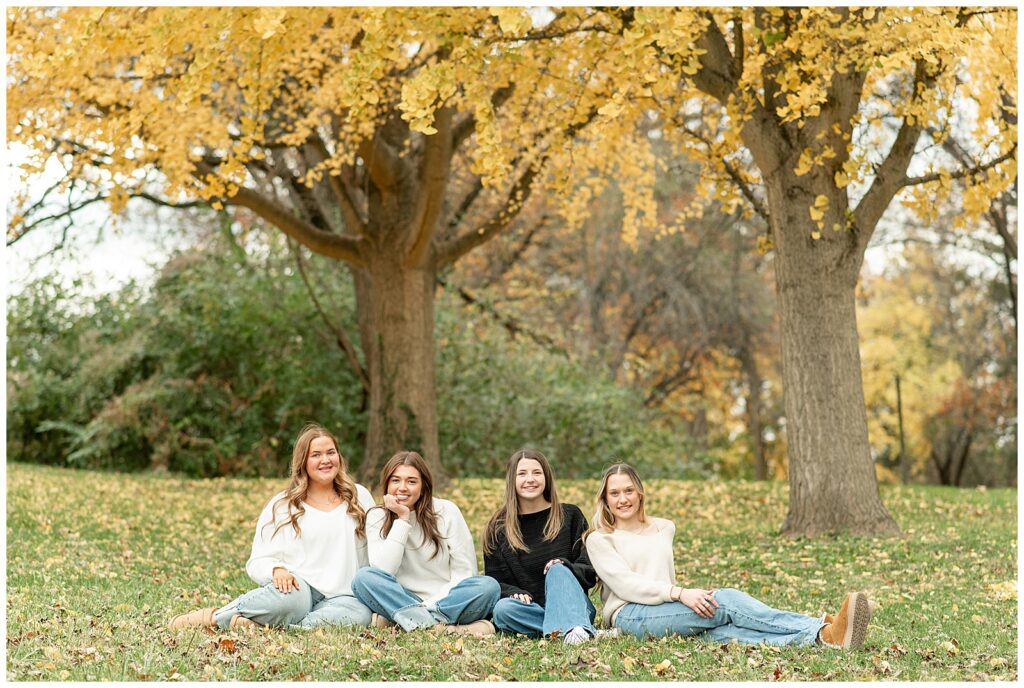 senior spokesmodel team sitting in grass by tree with yellow fall leaves for this Fall Senior Team Session in York PA