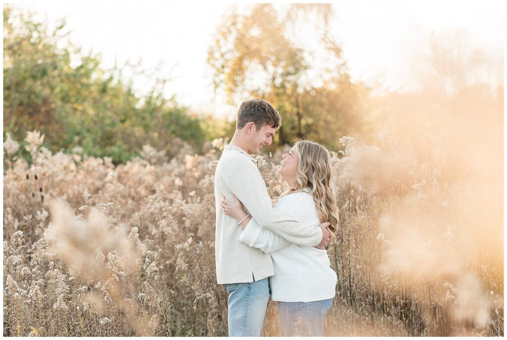 couple hugging by dried wildflowers for this Overlook Park Fall Engagement Session