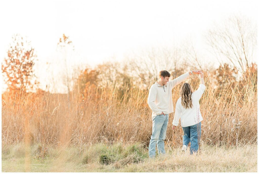 guy twirling girl under his left arm by field for this Overlook Park Fall Engagement Session