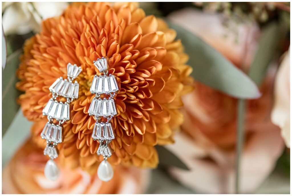 dangly diamond and pearl earrings atop orange flower for this Barn at Silverstone Fall Wedding