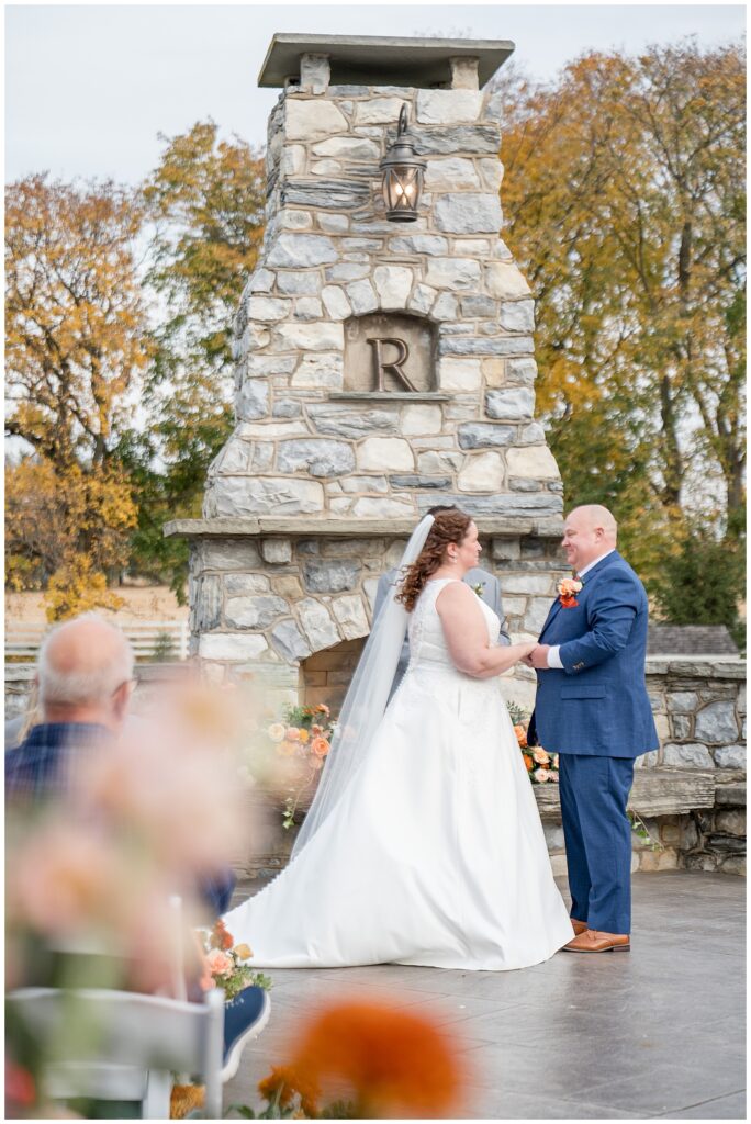 couple holding hands during outdoor wedding ceremony for this Barn at Silverstone Fall Wedding
