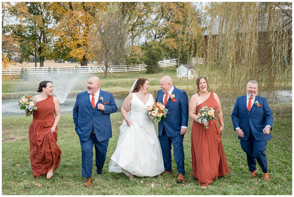 couple walking towards camera with bridal party for this Barn at Silverstone Fall Wedding