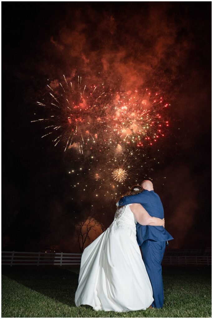 couple hugging as they watch fireworks at the end of their reception for this Barn at Silverstone Fall Wedding