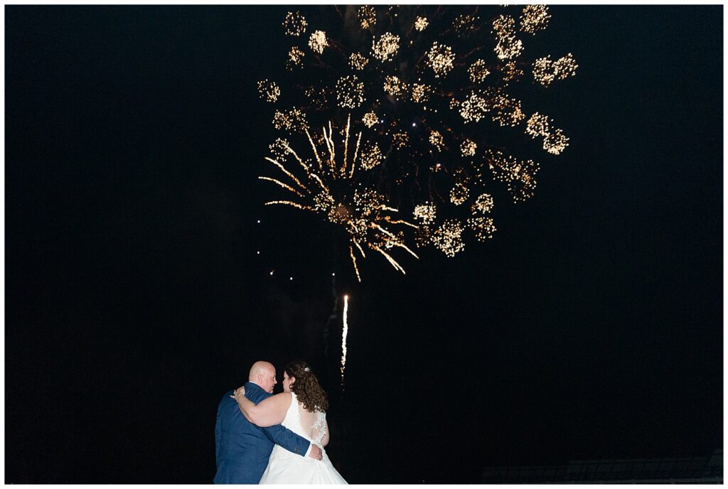 bride and groom hugging as they watch fireworks for this Barn at Silverstone Fall Wedding