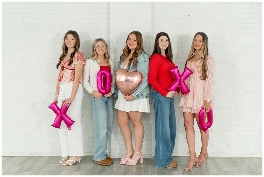 five senior girls holding valentines balloons with either their right or left shoulder toward camera for this Valentines Day BFF Shoot