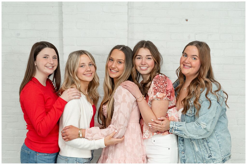 five girls huddled together and smiling at camera at the white room for this Valentines Day BFF Shoot