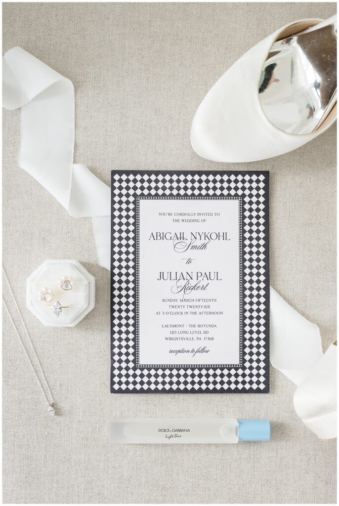 black and white buffalo print wedding invitation lying near wedding accessories for this Wedding at The Rotunda at Lauxmont Farms