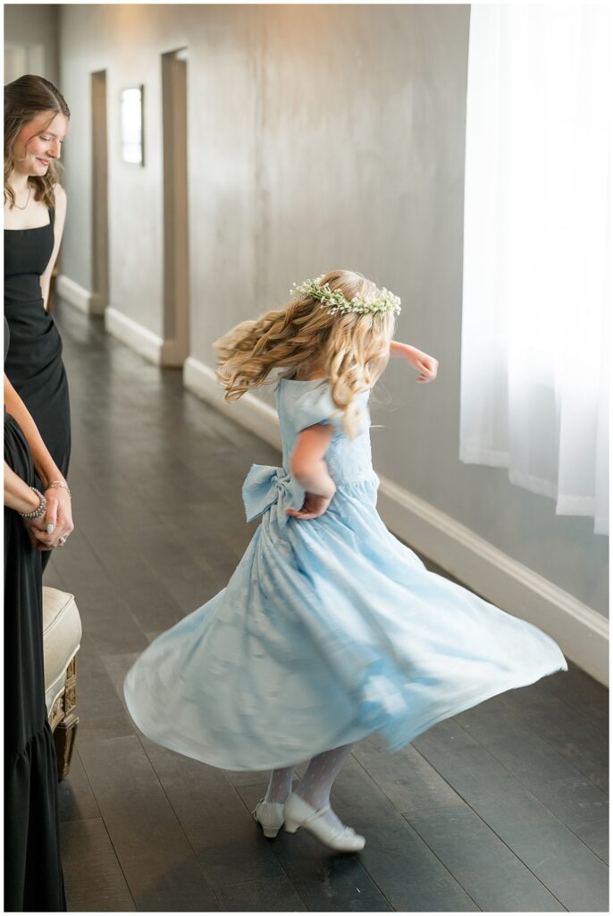 flower girl in baby blue gown twirling in circles in hallway for this Wedding at The Rotunda at Lauxmont Farms