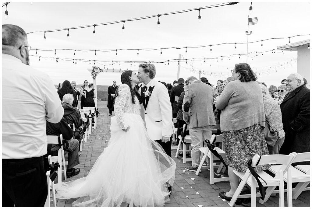 black and white image of couple kissing as they walk back the aisle leaving their ceremony for this Wedding at The Rotunda at Lauxmont Farms